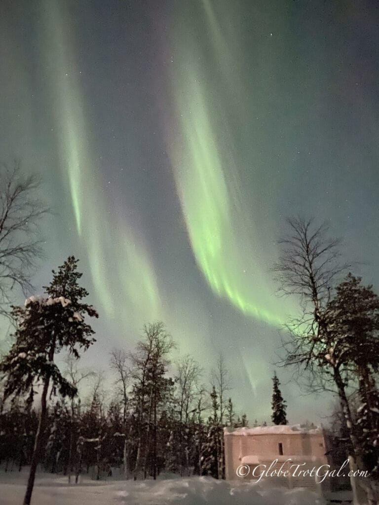Northern light above forest and cabin at Northern Lights Ranch in Levi Finland