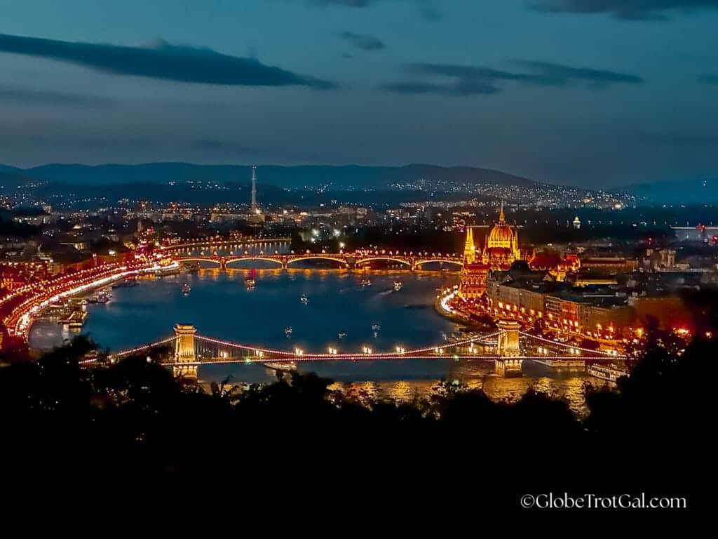 View over Budapest Hungary and the Danube River after dusk from Gellert Hill looking at illuminated Szechenyi chain bridge and the Hungarian Parliament building.