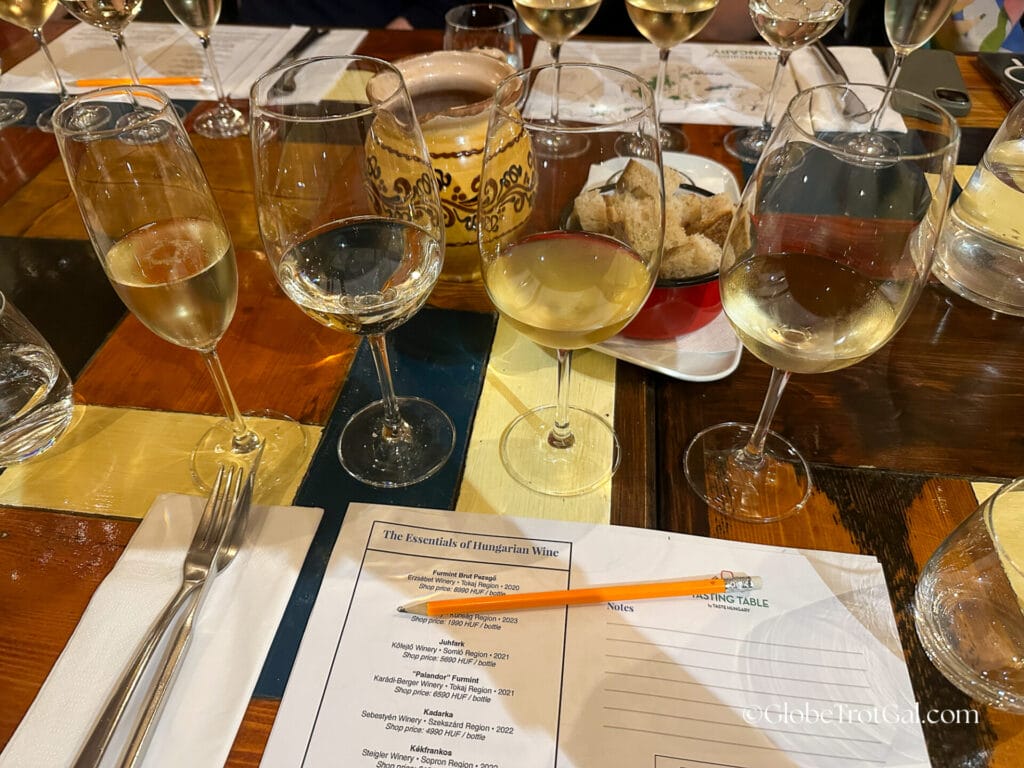 Four wine glasses filled with white wine on a table with a pencil and paper for taking notes at a wine tasting at Tasting Table wine shop in Budapest Hungary