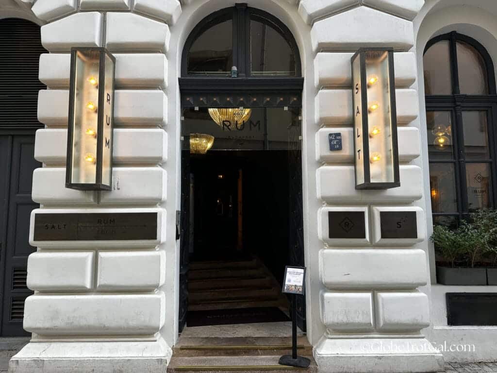 Exterior picture of the entrance door to a white stone building which is the Hotel Rum in Budapest Hungary