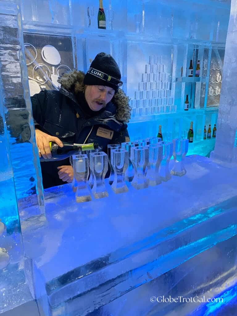Tour guide pouring champagne into flutes made of ice at the ice bar made of ice at the Icehotel in Jukkasjärvi, Sweden