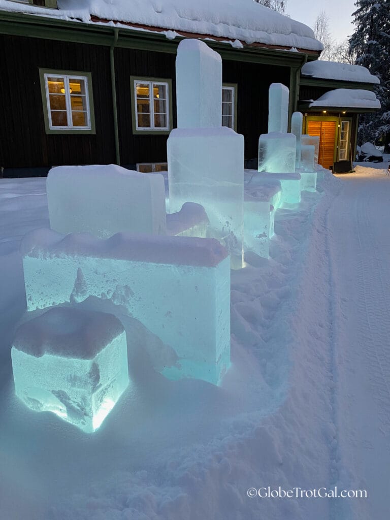 Blocks of lit up glowing ice leading to the entrance of a brown building at the Icehotel in Jukkasjärvi, Sweden