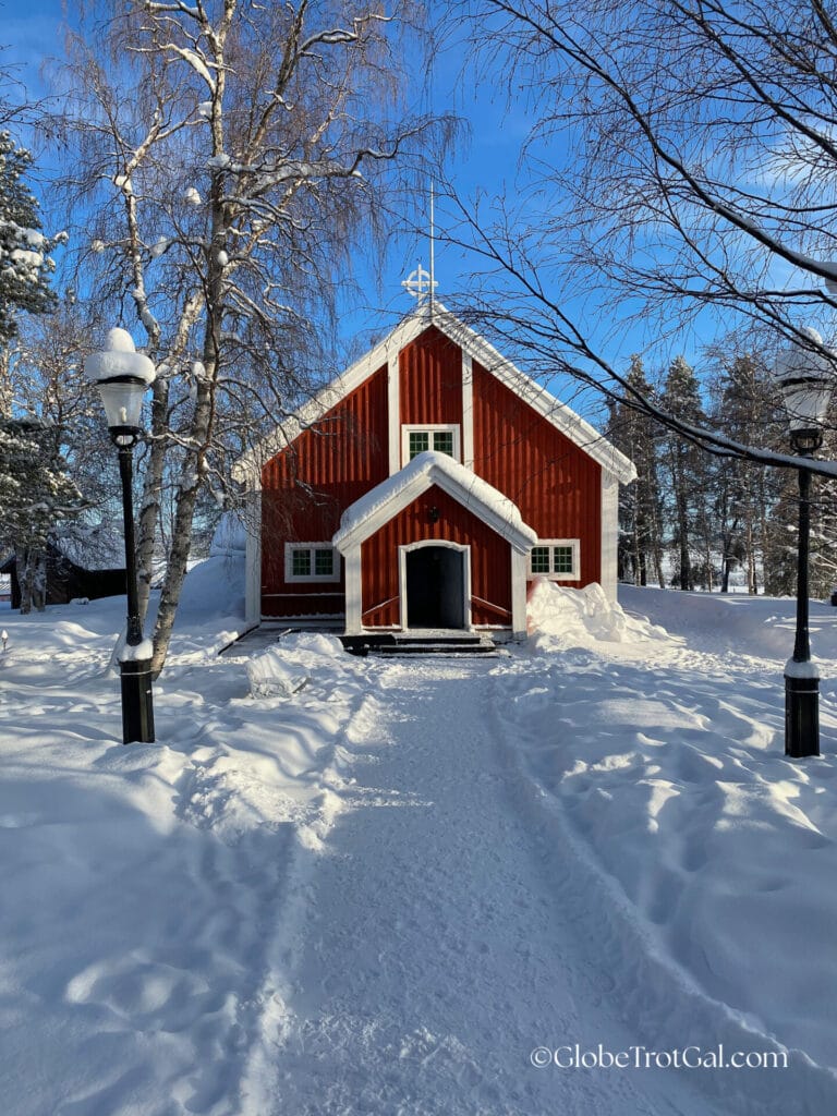 Small church with red siding and white trim surrounded by snow.