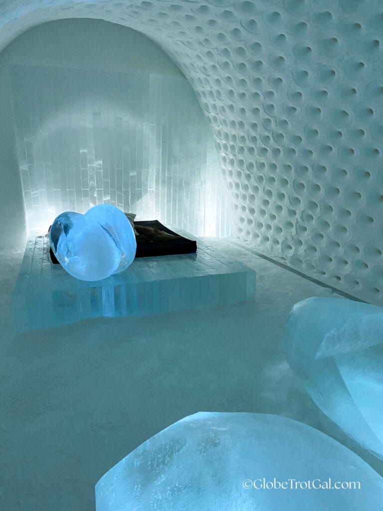 Block of clear ice with a mattress on it in a room carved of ice and snow at the Icehotel in Jukkasjärvi, Sweden