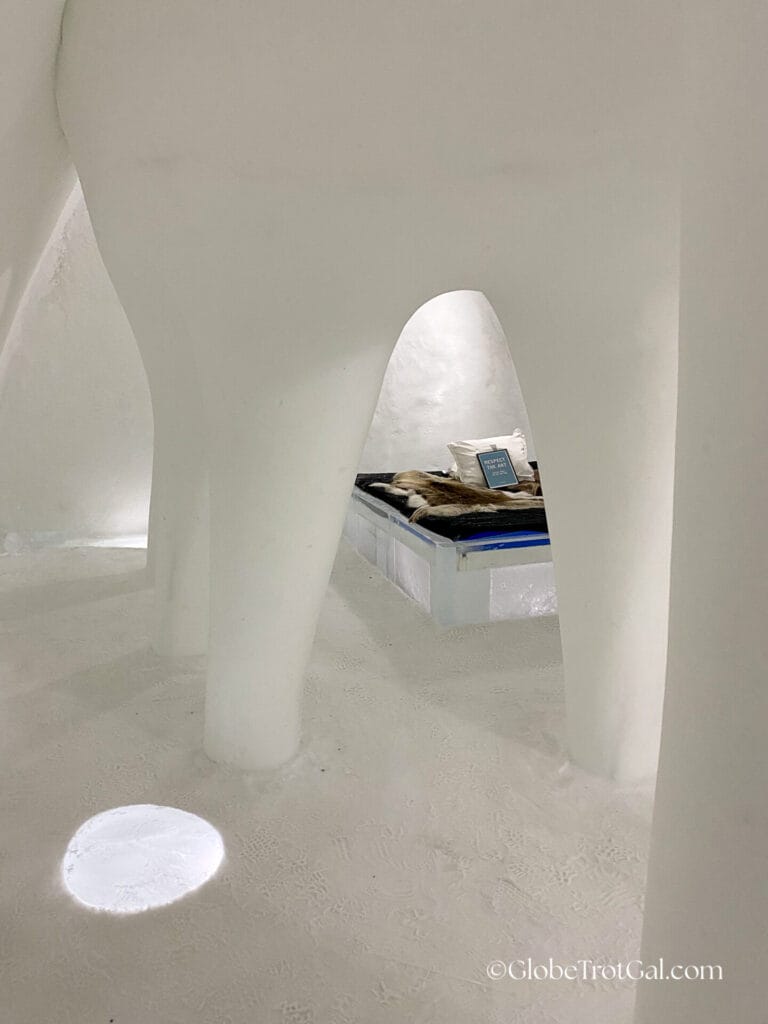 Giant tooth carved out of ice with a bed with an ice bed frame underneath it at the Icehotel in Jukkasjärvi, Sweden