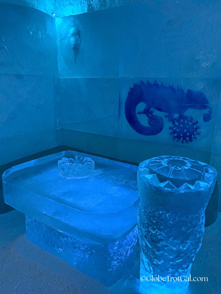 Ice table and ice walls with a carved lizard decoration at the Icehotel in Jukkasjärvi, Sweden