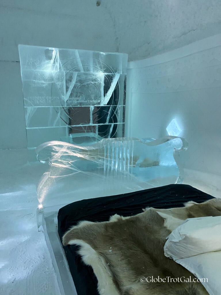 Bed frame made of clear carved ice and a mattress on top with reindeer hides covering it at the Icehotel in Jukkasjärvi, Sweden