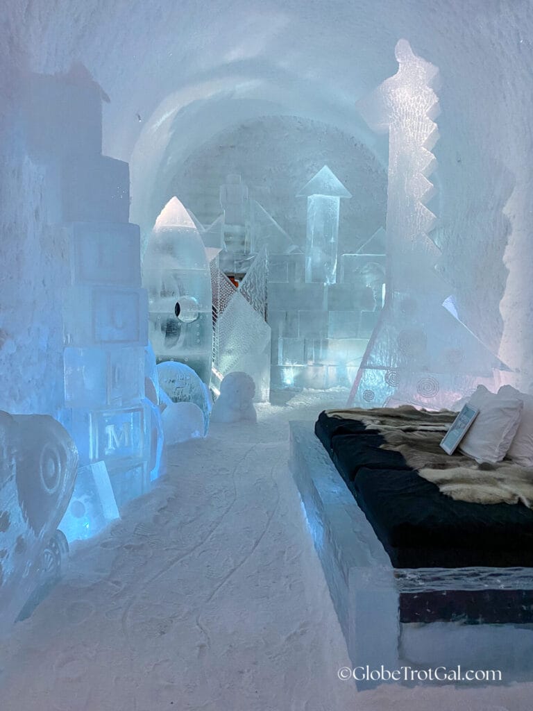 Ice suite room with carved blocks of ice with letters on them and a bed frame made of clear ice at the Icehotel in Jukkasjärvi, Sweden