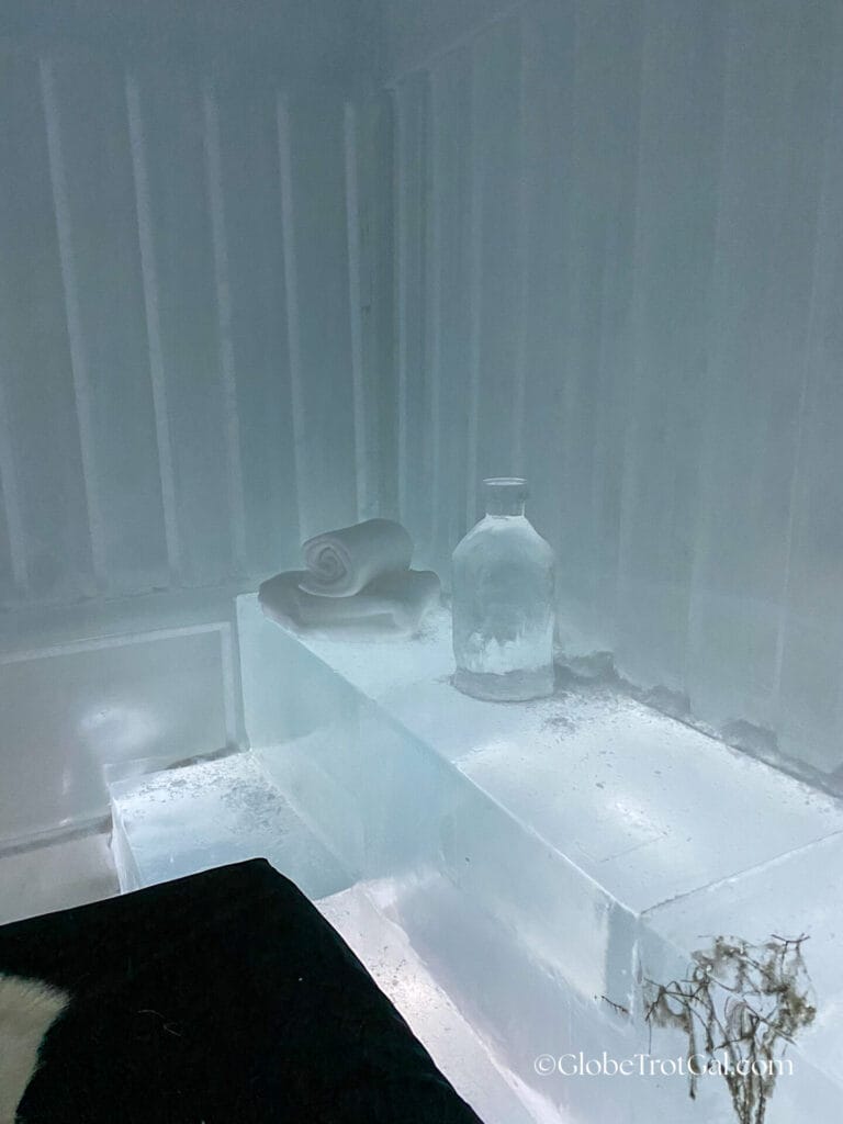 Walls and ledge made of ice with a towels and a jar carved out of ice on it at the Icehotel in Jukkasjärvi, Sweden