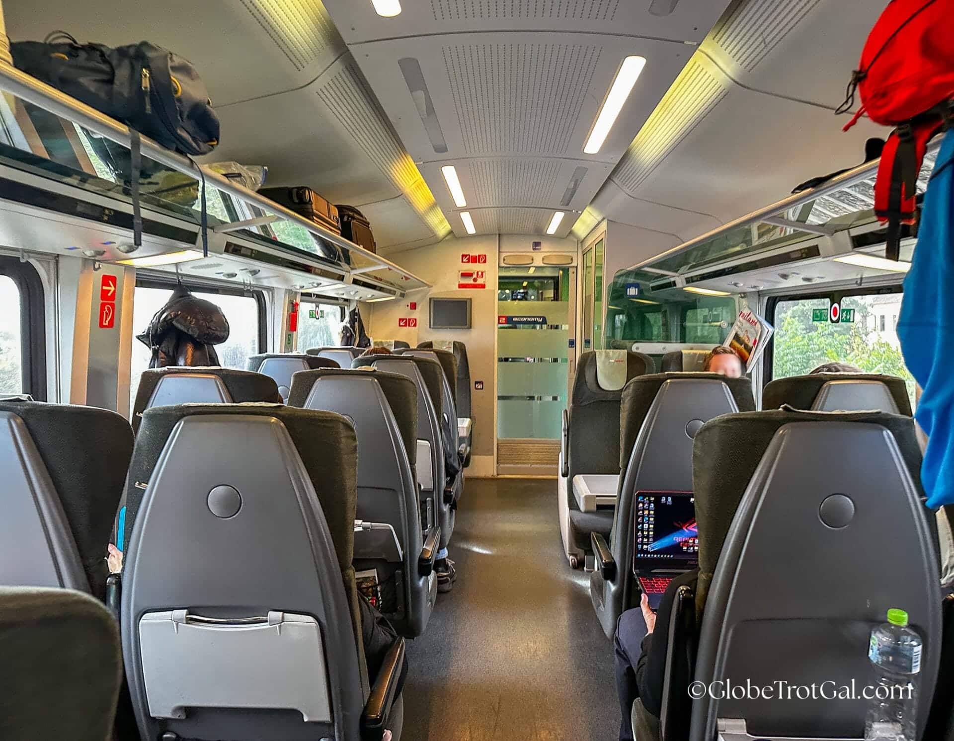 View looking down the aisle of OBB Railjet economy class train car with two gray seats on either side of the aisle.