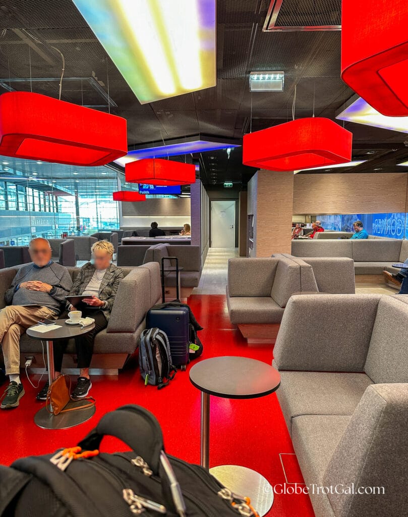 Gray couches and red floor and lighting in the Wien Hbf OBB Lounge
